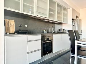 a kitchen with white cabinets and a stove at Precious Relaxation Rooms in Funchal in Funchal +17 photos