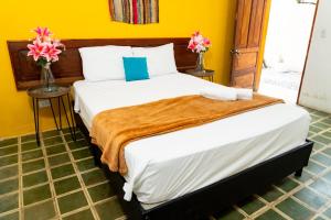 a bed in a room with two vases with flowers at Hotel Casa Real Villeta in Villeta
