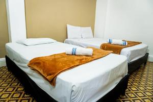 two beds in a hotel room with towels on them at Hotel Casa Real Villeta in Villeta