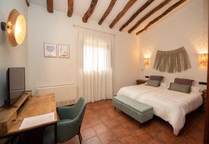 a bedroom with a bed and a desk and a television at Hotel Caseta Nova in Castalla