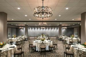 a banquet hall with white tables and chairs and a chandelier at Memphis Riverline Hotel in Memphis