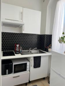 a white kitchen with a sink and a microwave at Petit cocon à 10 min de Paris in Cachan
