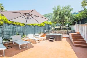 a patio with chairs and a table and an umbrella at Villa Al Borgo - Villa with Private Garden in Salerno