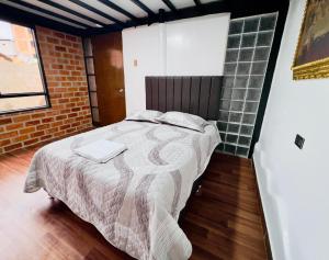 a bedroom with a bed and a brick wall at Casa raíz in Cusco