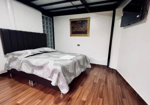 a bedroom with a bed and a painting on the wall at Casa raíz in Cusco