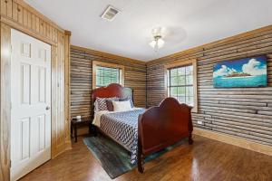 a bedroom with a bed in a room with wooden walls at Bacliff Family Getaway w/ Game Room + Private Pool in Bacliff +17 photos