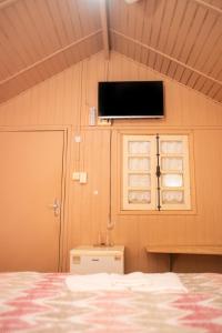 a room with a bed and a tv on the wall at Pousada Sabiá in Brotas