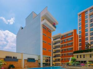 a tall white building next to some buildings at Mövenpick Hotel & Residences Nairobi in Nairobi