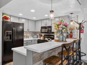 a kitchen with a refrigerator and a counter with chairs at Giant Steps 12 Rustic Retreat ski in out in Brian Head