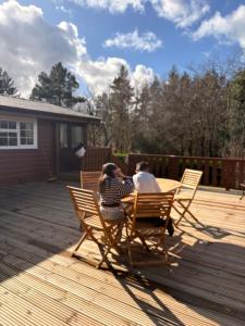 two people sitting at a table on a deck at Thistledonia in Trawsfynydd
