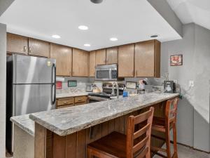 a kitchen with a stainless steel refrigerator and wooden cabinets at Giant Steps 28 Ski in out in Brian Head