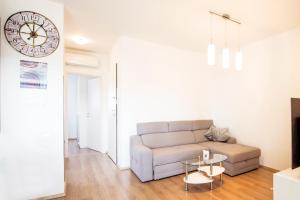 a living room with a couch and a clock on the wall at Apartman Denis in Pula