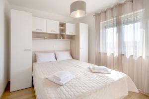 a bedroom with a white bed with two towels on it at Apartman Denis in Pula