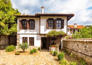 a white house with a stone wall at Къща за гости Старият Град Златоград in Zlatograd