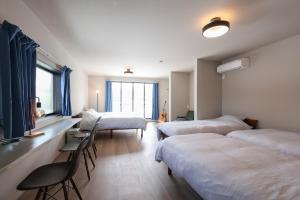 a room with four beds and a table and chairs at Unite in Myoko in Taguchi