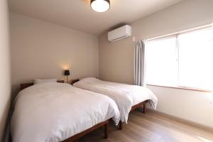 two beds in a white room with a window at Unite in Myoko in Taguchi