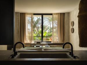 a bedroom with a bed and a large window at Esh Hotel & Spa, a Member of Design Hotels in Nosara