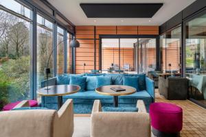 a living room with a blue couch and tables at Lyon Marriott Hotel Cité Internationale in Lyon