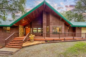 a log home with a large porch and a green roof at Summit Cabin Stunning home Loaded with amenities in Oakhurst