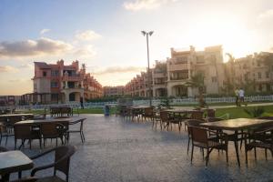 an outdoor patio with tables and chairs and buildings at Lazorde Bay Apartment in El Alamein