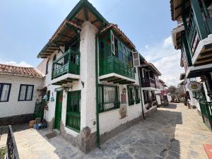 ein altes Gebäude mit grünen Türen und Fenstern an einer Straße in der Unterkunft Hostal La Cestería Pueblito Boyacense in Duitama
