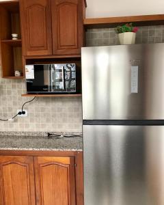 a stainless steel refrigerator in a kitchen with wooden cabinets at Plaza Mitre, departamento 2 dormitorios in San Nicolás de los Arroyos