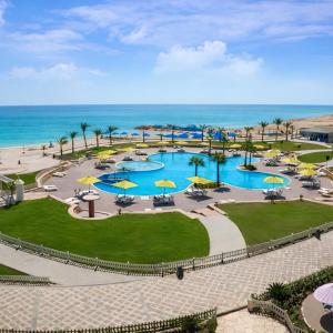 an aerial view of a pool with umbrellas and the ocean at Lazorde Bay Apartment in El Alamein