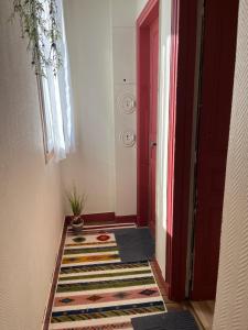 a hallway with a red door and a rug at Petit cocon à 10 min de Paris in Cachan +1 photo
