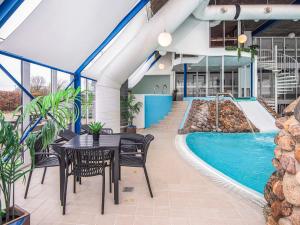 a patio with a table and chairs next to a swimming pool at 4 person holiday home on a holiday park in Hejls in Hejls