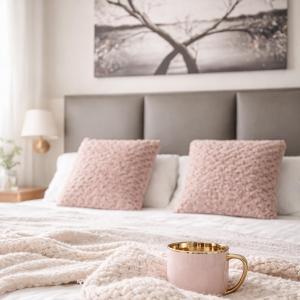 a bed with pink pillows and a cup on it at Morska Fala in Pobierowo