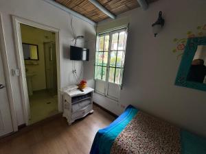 ein Schlafzimmer mit einem Bett, einem Fenster und einem Spiegel in der Unterkunft Hostal La Cestería Pueblito Boyacense in Duitama