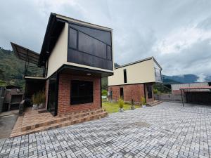 a house with a brick and glass facade at Relajate en una TinyHouse privada en Baños de Agua Santa con Jacuzzi y vistas increíbles in Baños