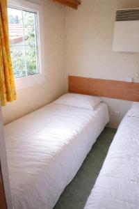 two beds in a small room with a window at Mobil-home tout équipé Le Castellet les pins doux 2 in Le Castellet