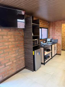 a kitchen with a refrigerator and a brick wall at Relajate en una TinyHouse privada en Baños de Agua Santa con Jacuzzi y vistas increíbles in Baños +10 photos