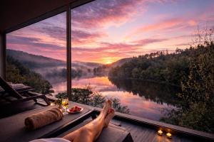 a person laying on a window sill looking out at a lake at Hotel Rural Quinta da Conchada in Aguieira