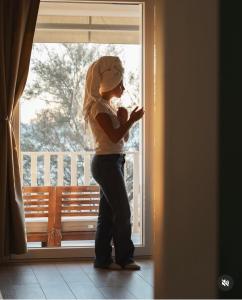 a woman standing by a window looking at her cell phone at Life House B&B in Follonica +32 photos