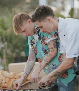 two men with tattoos are looking at a grill at Life House B&B in Follonica