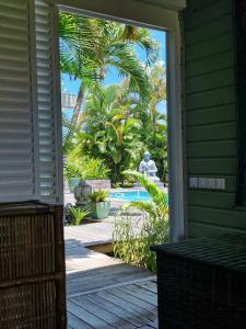 a porch with a view of a pool and palm trees at Habitation Tara in Capesterre-Belle-Eau