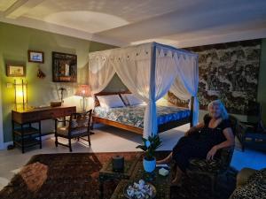 a woman sitting in a chair in a bedroom at Habitation Tara in Capesterre-Belle-Eau