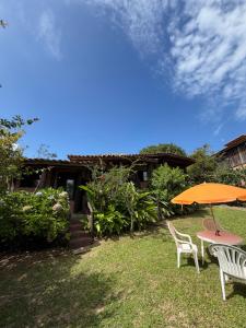 two chairs and a table with an umbrella on a yard at Encanto do Mar Praia do Rosa in Praia do Rosa