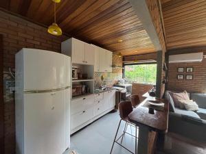 a kitchen with a white refrigerator and a table at Casa Reserva da Gávea Visconde de Mauá in Visconde De Maua