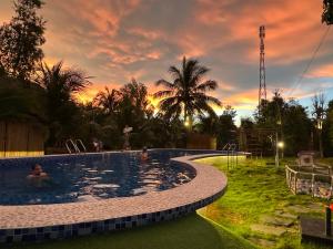 a pool with people in it with a sunset in the background at Rustic Homeaway - Stay with the local in Phong Ðiền