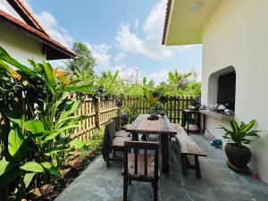 a patio with a wooden table and chairs and a fence at Rustic Homeaway - Stay with the local in Phong Ðiền