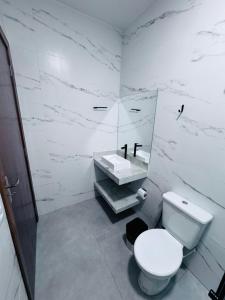 a white bathroom with a toilet and a sink at Hotel Luxx in Sinop