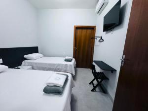 a room with two beds and a desk and a television at Hotel Luxx in Sinop