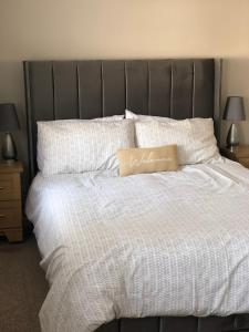 a large bed with white sheets and a gray headboard at Moat View Donaghadee in Donaghadee