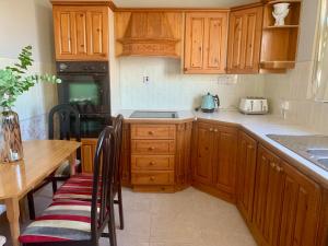 a kitchen with wooden cabinets and a wooden table and a table and chairs at Azure Lodge in Bundoran