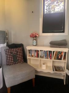 a room with a book shelf with a tv and a chair at Adorable studio cottage with mountain views in Staveley