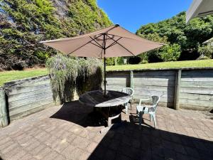 a table and chairs with an umbrella on a patio at Ridgehaven Accommodation in Opotiki