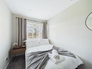 a bedroom with a bed with white sheets and a window at The Costwold Haven in Shurdington